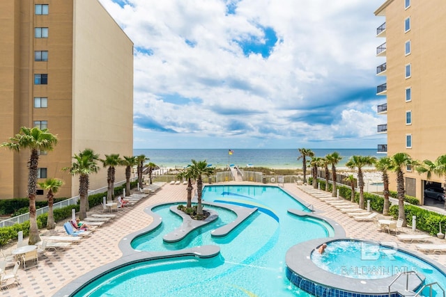 view of pool with a patio area, fence, and a water view