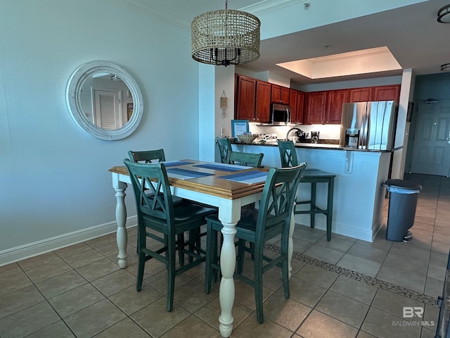 dining area featuring an inviting chandelier, a tray ceiling, light tile patterned floors, and baseboards