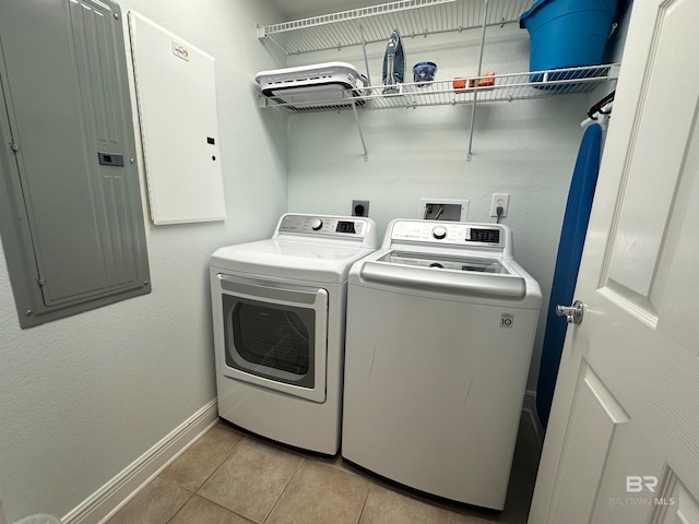 laundry area with electric panel, light tile patterned flooring, baseboards, laundry area, and washing machine and clothes dryer