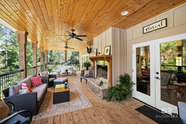 wooden deck with an outdoor living space with a fireplace, ceiling fan, and french doors