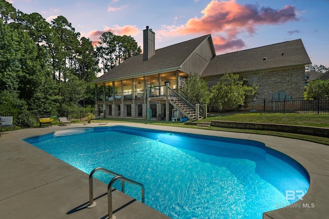 pool at dusk with a patio area