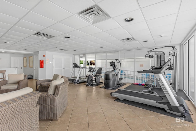 workout area featuring a drop ceiling and light tile patterned floors