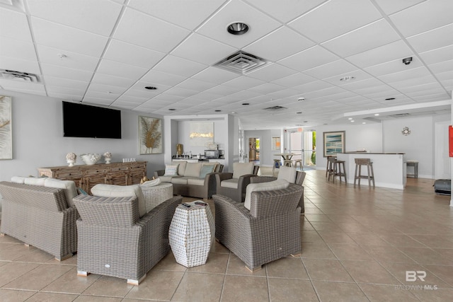 tiled living room featuring a drop ceiling