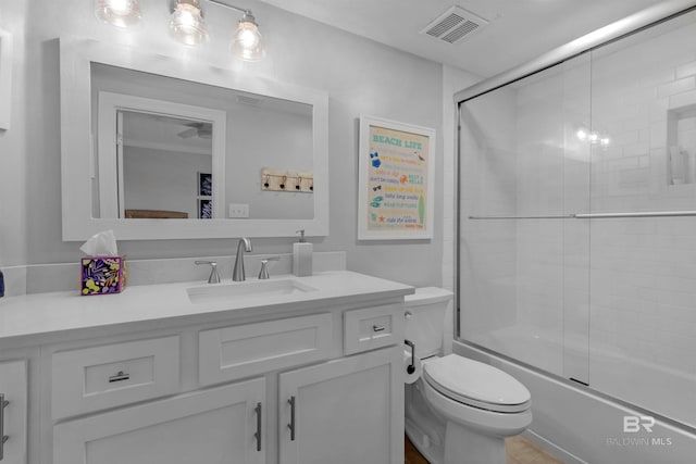 full bathroom featuring combined bath / shower with glass door, vanity, and toilet