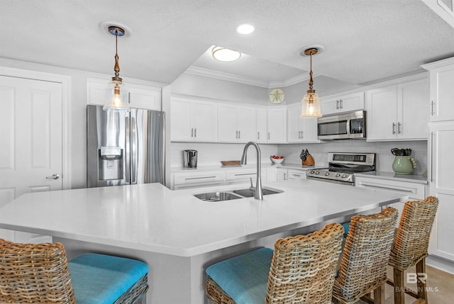 kitchen featuring white cabinets, a kitchen island with sink, stainless steel appliances, and a kitchen bar