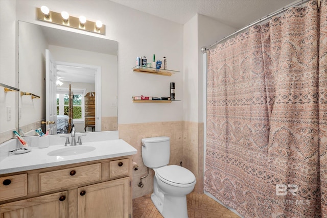 bathroom with vanity, a textured ceiling, walk in shower, tile walls, and toilet