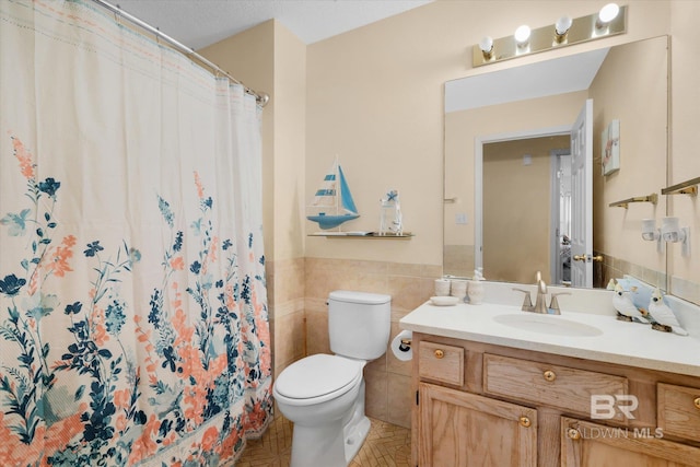 bathroom with tile walls, curtained shower, vanity, and toilet