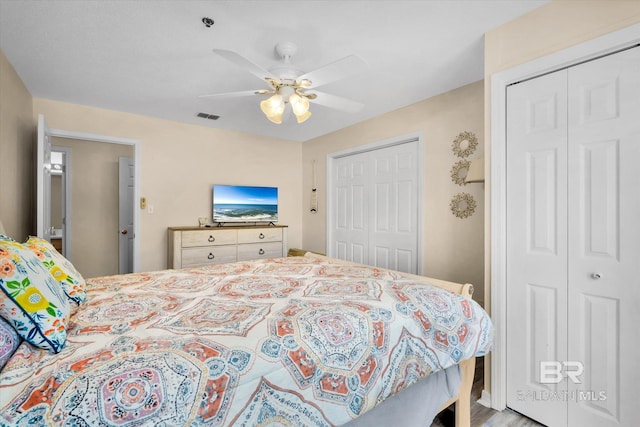 bedroom featuring light hardwood / wood-style flooring, multiple closets, and ceiling fan