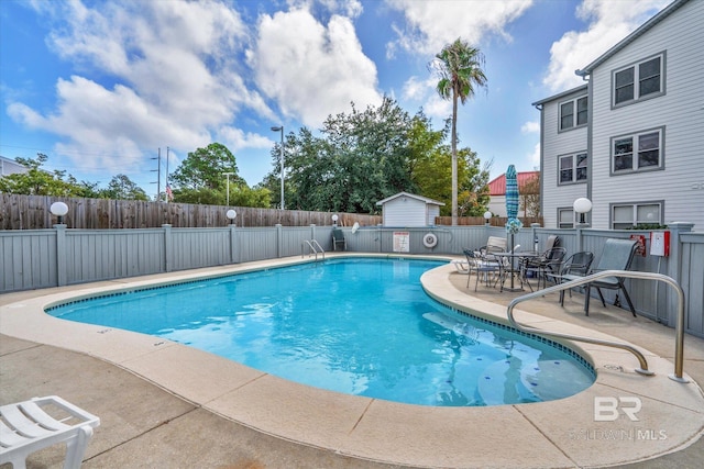 view of pool featuring a patio and a storage shed