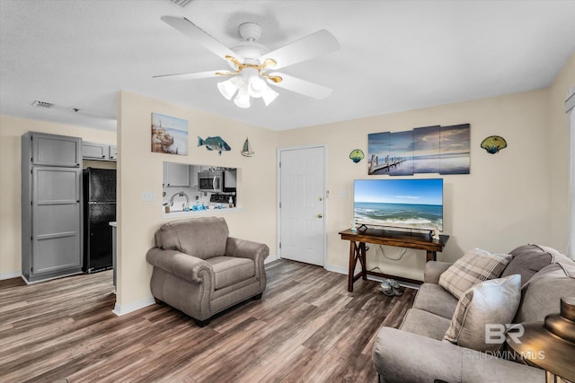 living room featuring ceiling fan and dark hardwood / wood-style flooring