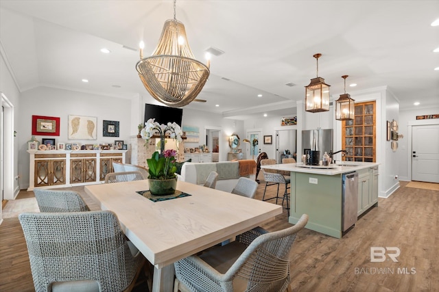 dining area with a chandelier, light hardwood / wood-style floors, lofted ceiling, crown molding, and sink