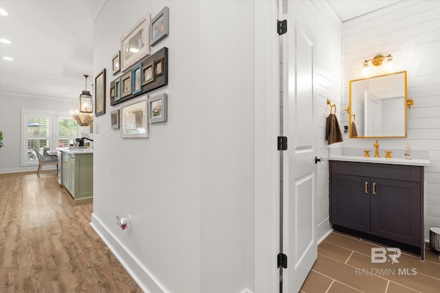 hall featuring sink, a notable chandelier, and crown molding