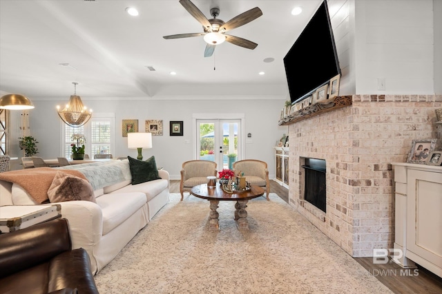 living room with ceiling fan with notable chandelier, french doors, a fireplace, and hardwood / wood-style floors