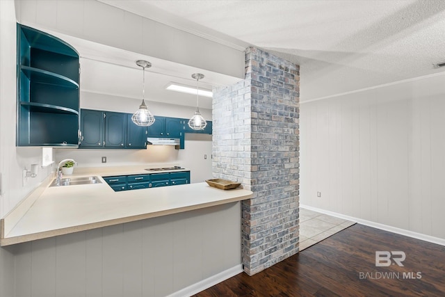 kitchen featuring sink, blue cabinetry, hanging light fixtures, dark hardwood / wood-style floors, and kitchen peninsula