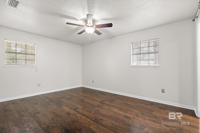 empty room with ceiling fan, a textured ceiling, dark hardwood / wood-style floors, and a healthy amount of sunlight