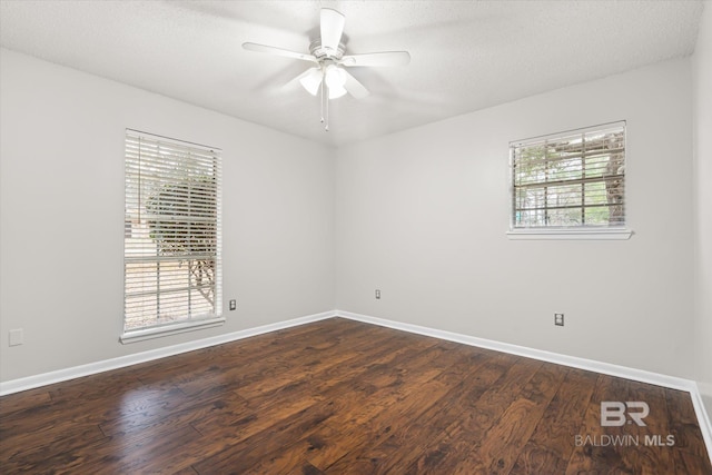 empty room with dark wood-type flooring, ceiling fan, plenty of natural light, and a textured ceiling