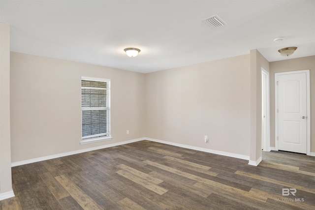 empty room with visible vents, baseboards, and dark wood-style floors