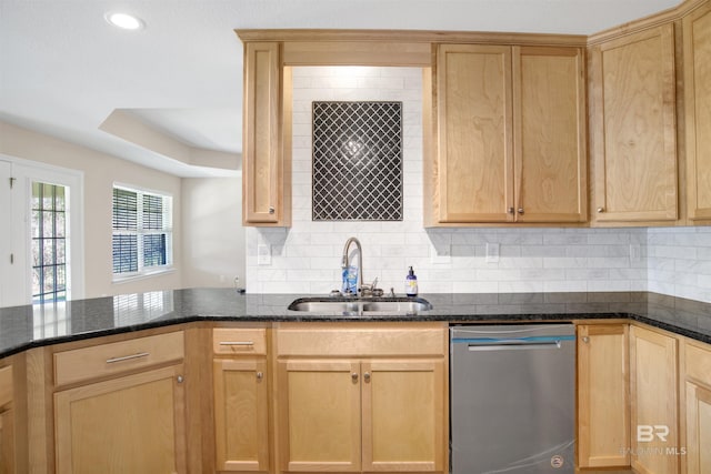 kitchen with light brown cabinetry, dark stone countertops, dishwasher, and a sink