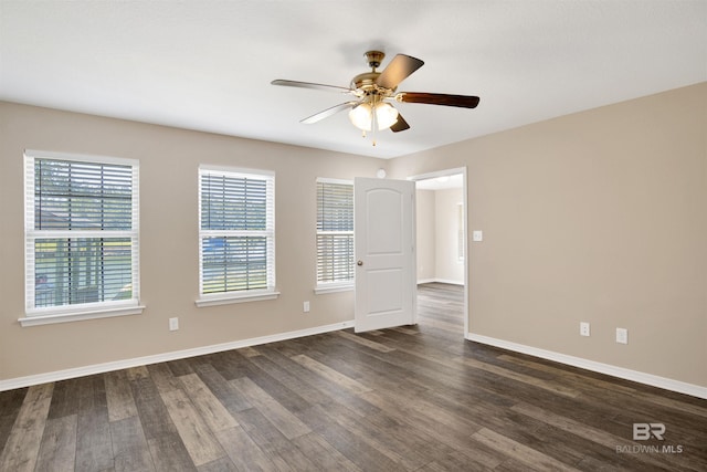 spare room with a ceiling fan, dark wood-style floors, and baseboards