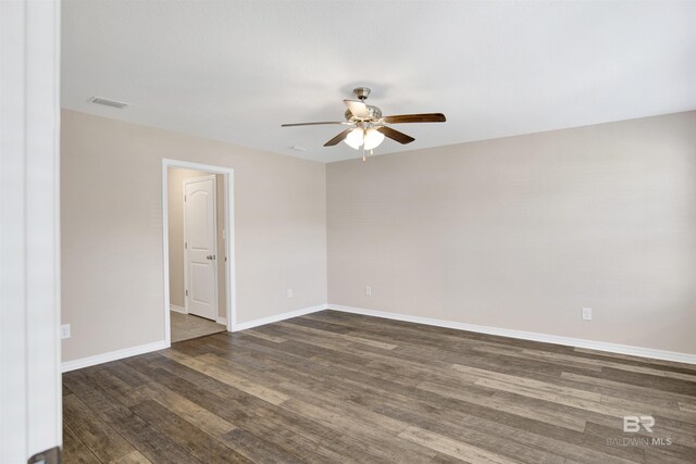 unfurnished room with dark wood finished floors, visible vents, ceiling fan, and baseboards