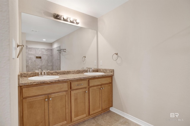 full bathroom with a sink, baseboards, tiled shower, and double vanity