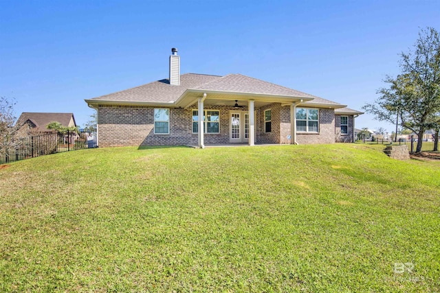 back of house featuring fence, a yard, brick siding, ceiling fan, and a chimney