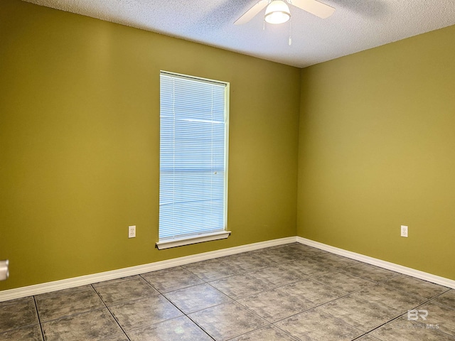 unfurnished room with ceiling fan, tile patterned flooring, baseboards, and a textured ceiling