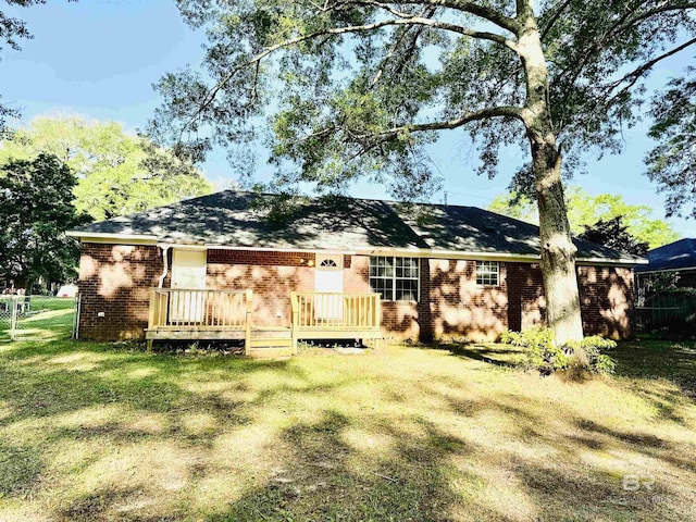 rear view of house with a yard, a wooden deck, fence, and brick siding