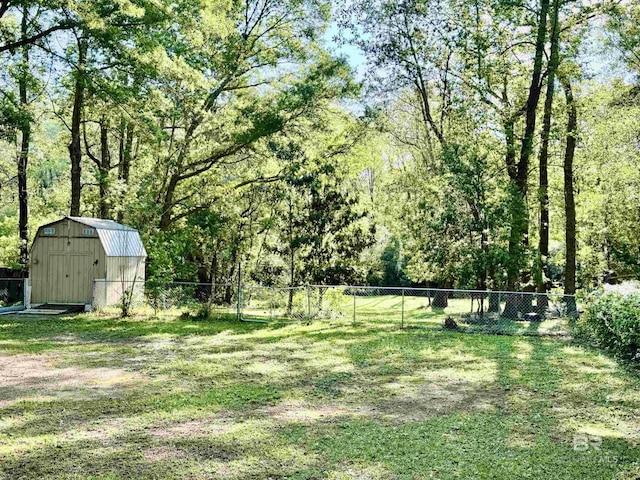 view of yard with a view of trees, a shed, a fenced backyard, and an outdoor structure