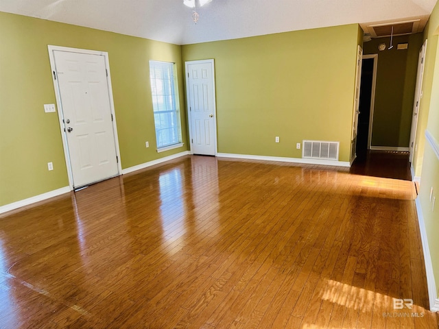 empty room with visible vents, baseboards, attic access, and hardwood / wood-style floors