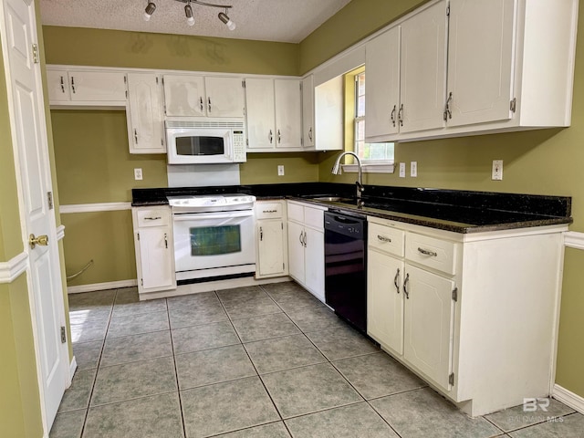 kitchen featuring light tile patterned floors, dark countertops, white appliances, and a textured ceiling