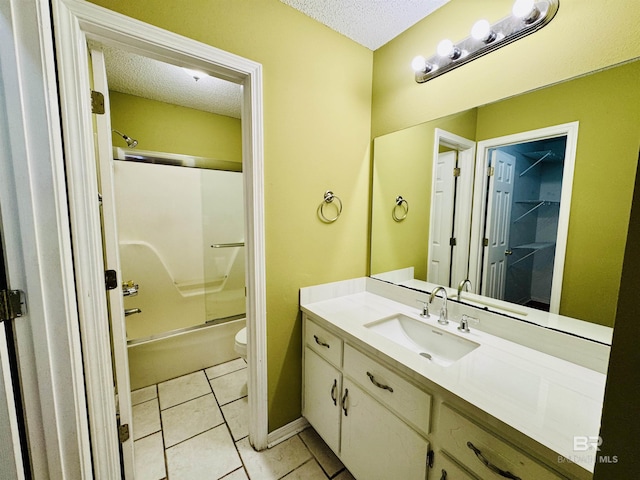 bathroom featuring bath / shower combo with glass door, vanity, tile patterned flooring, and a textured ceiling