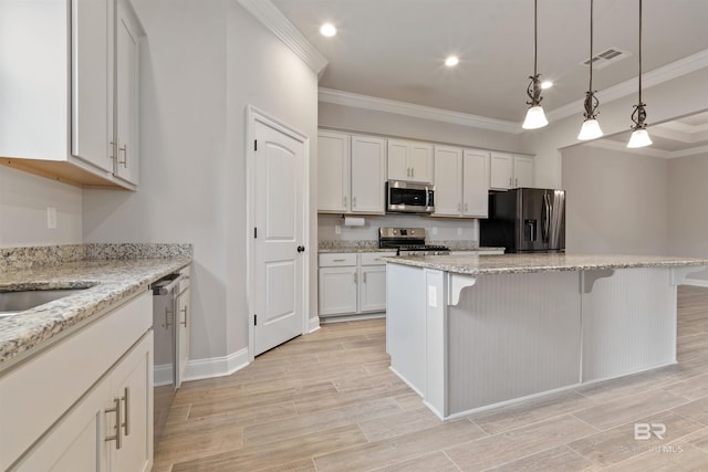 kitchen with a kitchen bar, stainless steel appliances, white cabinetry, and light hardwood / wood-style flooring