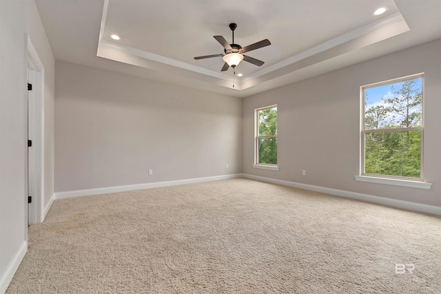 carpeted empty room with ceiling fan, crown molding, and a tray ceiling