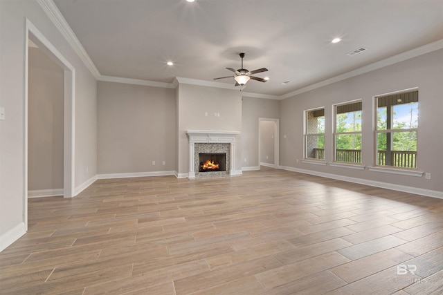 unfurnished living room featuring ceiling fan, light hardwood / wood-style flooring, a high end fireplace, and crown molding