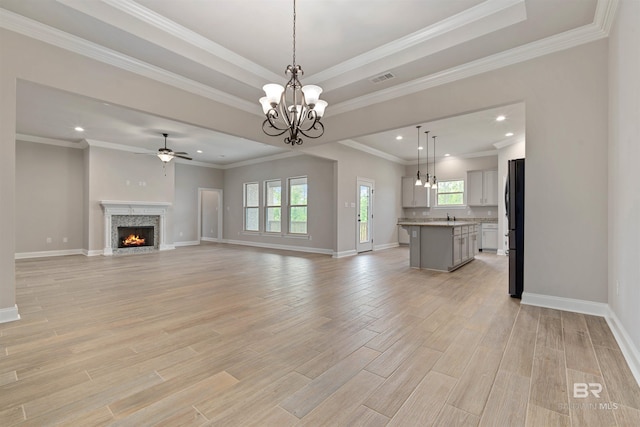 unfurnished living room with a healthy amount of sunlight, crown molding, light wood-type flooring, and a fireplace