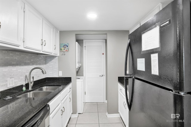 kitchen with stacked washer and dryer, light tile patterned floors, dishwasher, freestanding refrigerator, and a sink