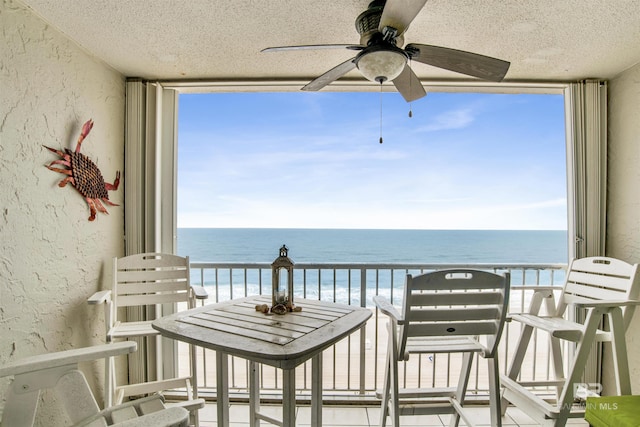 balcony with a water view and a ceiling fan