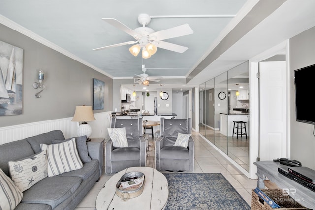 living room featuring wainscoting, light tile patterned flooring, a ceiling fan, and crown molding