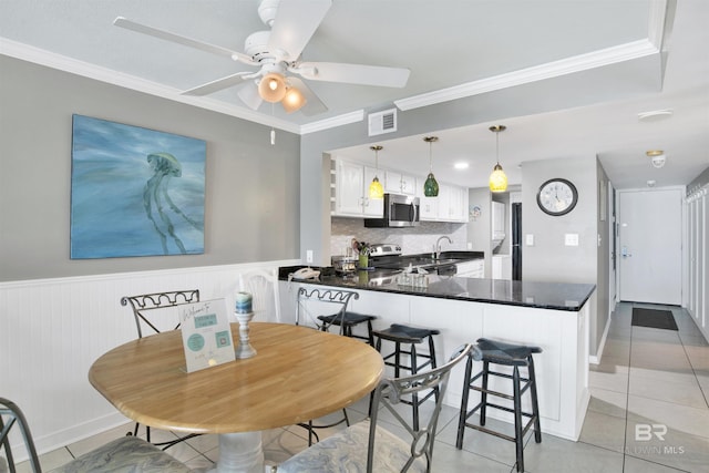 kitchen featuring stainless steel appliances, dark countertops, visible vents, and crown molding