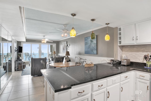 kitchen with light tile patterned flooring, a peninsula, white cabinetry, dark stone counters, and pendant lighting