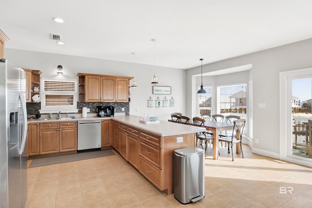 kitchen featuring pendant lighting, light tile floors, a healthy amount of sunlight, backsplash, and stainless steel appliances