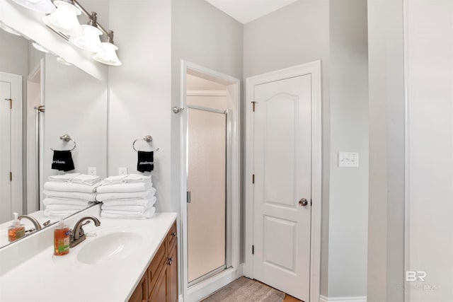 bathroom with an enclosed shower, wood-type flooring, and vanity with extensive cabinet space