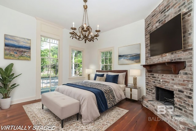 bedroom with an inviting chandelier, access to exterior, dark hardwood / wood-style flooring, and a fireplace