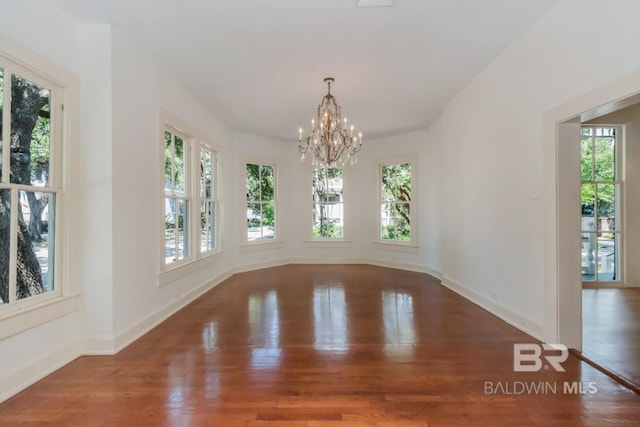 unfurnished dining area with wood-type flooring and a notable chandelier