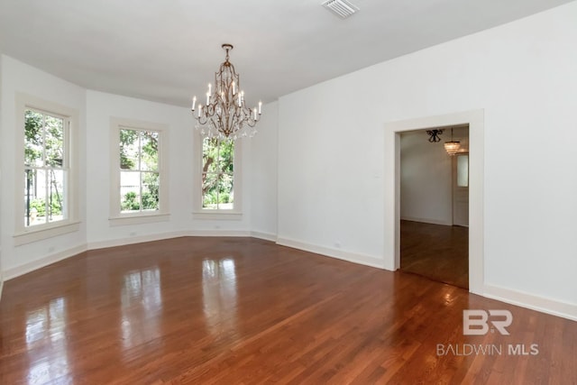 empty room featuring an inviting chandelier and dark hardwood / wood-style floors