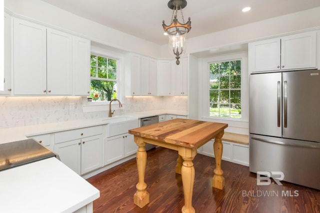 kitchen with sink, stainless steel appliances, white cabinets, decorative light fixtures, and decorative backsplash