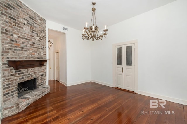 unfurnished living room with a chandelier, a fireplace, and dark hardwood / wood-style floors