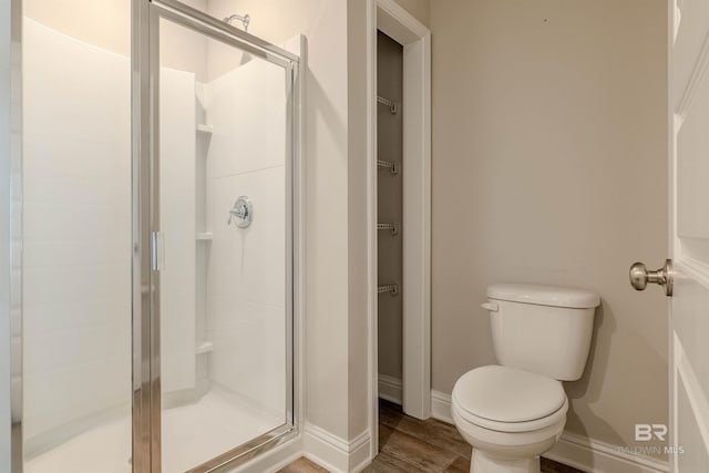 bathroom with wood-type flooring, toilet, and a shower with shower door