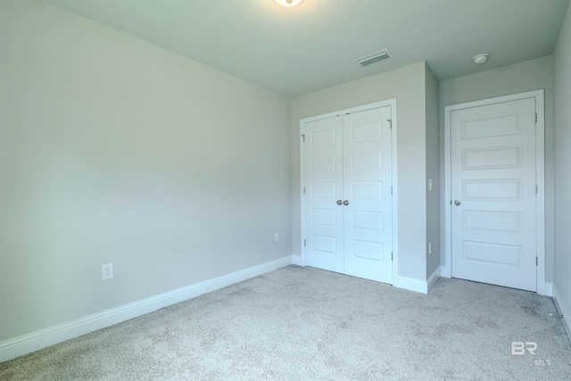 unfurnished bedroom featuring light colored carpet and a closet